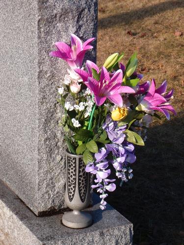 flower-adorned gravestone at St Louis De Gonzaque Cemetery in New Hampshire