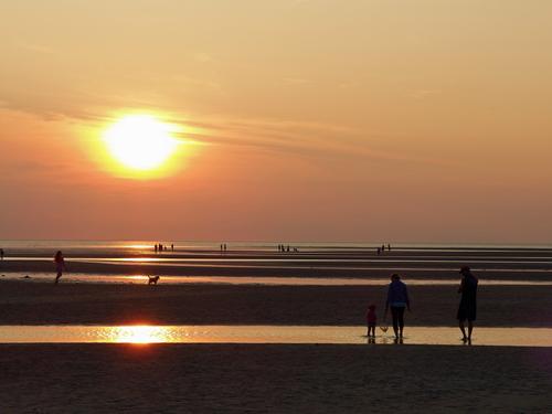 tourists enjoying sunset and low tide at Skaket Beach on the inner coast of Cape Cod in eastern Massachusetts