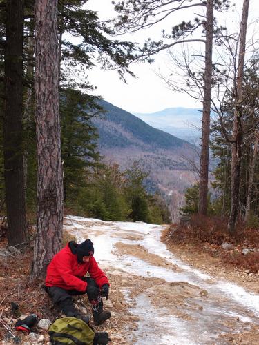 a hiker dons MicroSpikes to negotiate an icy ATV track on Nickerson Mountain in New Hampshire