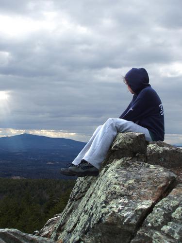 hiker on the cliff of North Pack Monadnock Mountain in New Hampshire with a view of Mount Monadnock