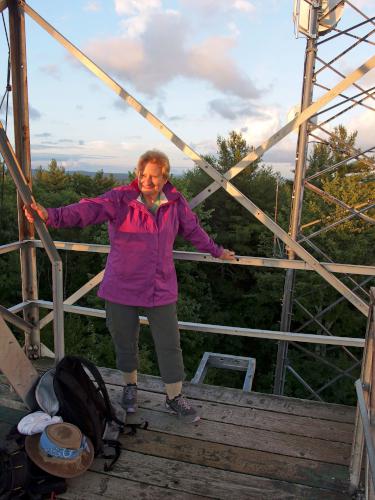 Andee on the fire tower at sunset atop Oak Hill near Concord in New Hampshire