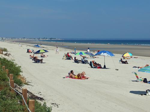 tourists enjoy great weather and low tide on the sandy beach across the dune from Ogunquit River in southern coastal Maine