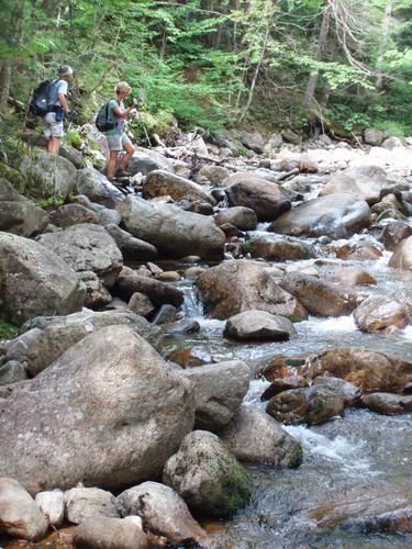 hikers crossing a stream on the way to Owl's Head in New Hampshire