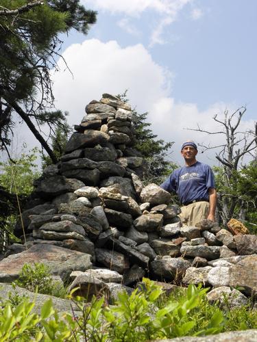 hiker and cairn on the summit of Parker Mountain in New Hampshire