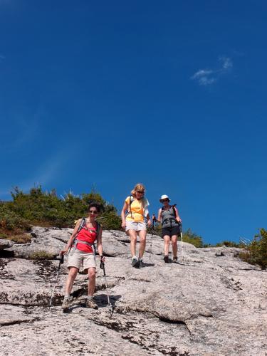 hikers descending the summit dome of North Percy Peak in New Hampshire