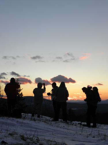 winter hikers on Pinnacle Mountain at sunset in New Hampshire