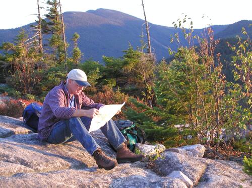 a hiker checks the map on Potash Mountain summit in New Hampshire