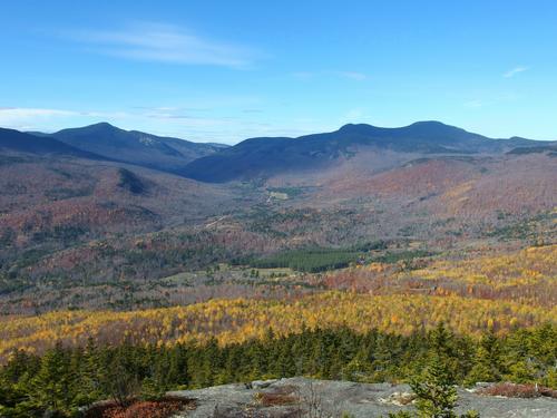 westerly view from Puzzle Mountain in western Maine of Route 26 snaking 
up Grafton Notch between Baldpate Moutain's 
double peak looming on the right and Old Speck Mountain on the far horizon