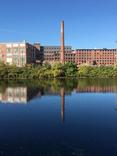 old chimney and mill buildings viewed from the Nashua Riverwalk in New Hampshire