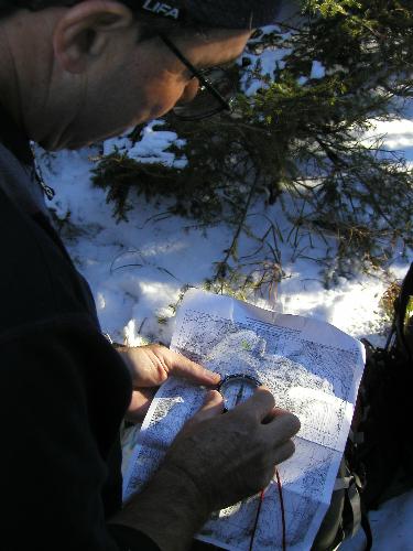 a bushwhacker checks map and compass on the way to Sable Mountain in New Hampshire