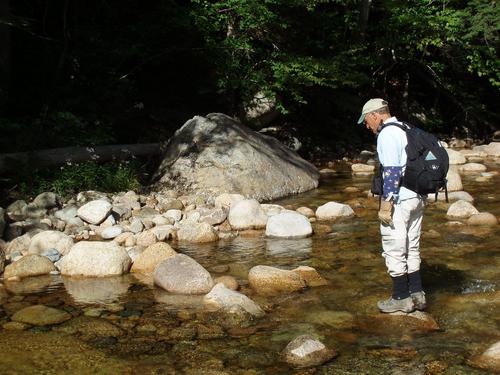 hiker crossing the Hancock Branch of the Pemigewasset River in New Hampshire