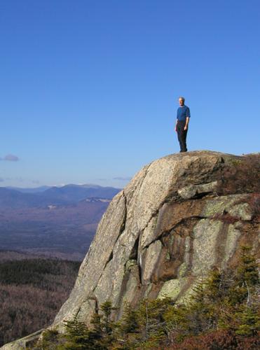 hiker on a cliff near the summit of First Sister Mountain in New Hampshire