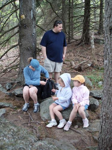 hikers take a snack break on the trail to Skatutakee Mountain in New Hampshire