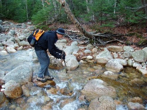 hiker crossing Downes Brook in New Hampshire