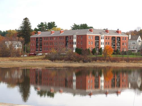 an apartment building reflected on the Squamscott River near Swazey Parkway at Exeter in southern New Hampshire