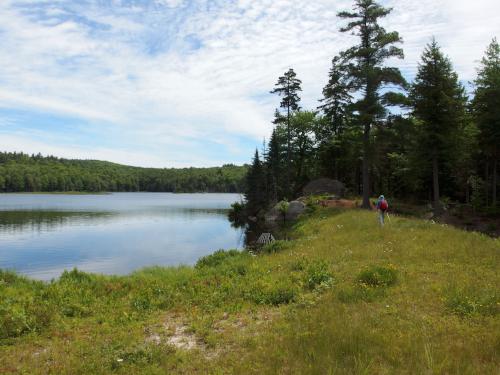 John walks the edge of Pioneer Lake in June near Stoddard Rocks in southern New Hampshire