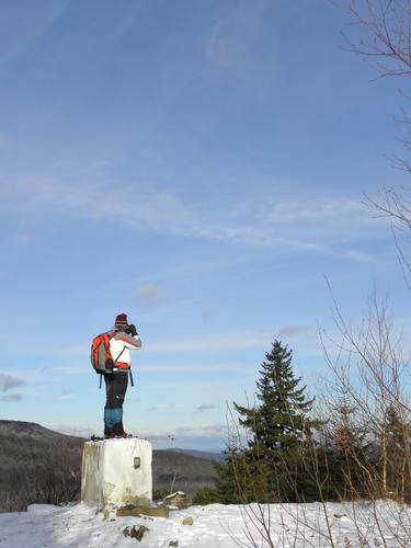 hiker stepping up for a photo on Temple Mountain in New Hampshire