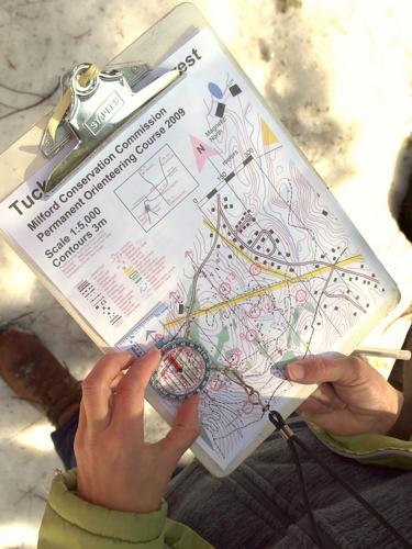 Kate uses map-and-compass to find one of the Orienteering Course markers at Tucker Brook Town Forest in New Hampshire