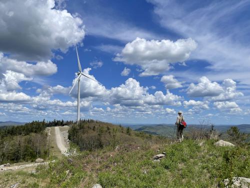 a hiker and wind turbine in May on Tuttle Hill in southwestern New Hampshire
