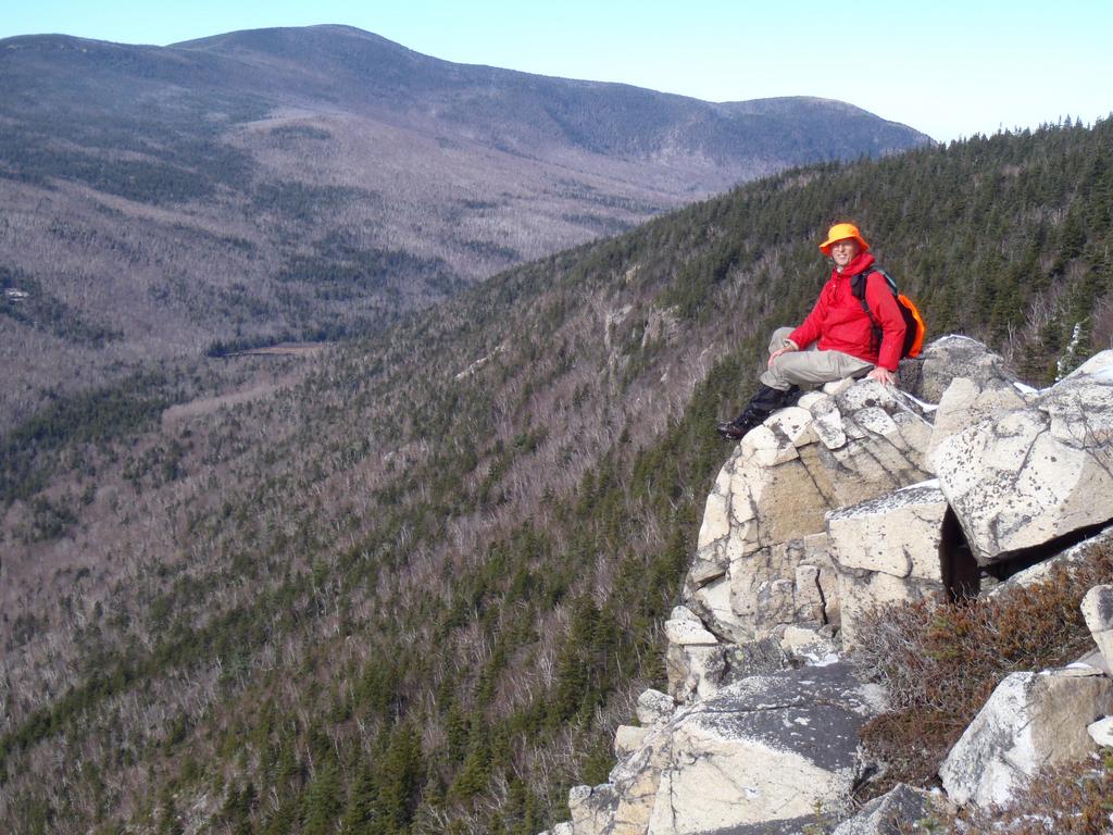 hiker atop the cliff on Whitewall Mountain overlooking Zealand Notch in New Hampshire