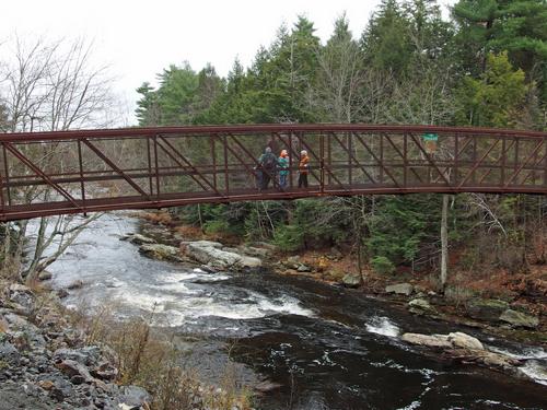 hikers on the pedestrian bridge crossing over the Souhegan River near Wildcat Falls at Merrimack in New Hampshire