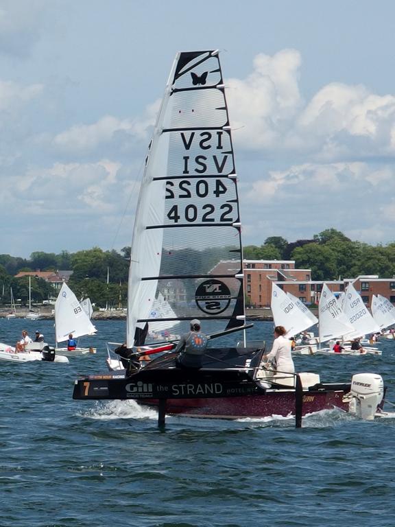 a high-tech hydrofoil sailboat zips past a ho-hum motorboat at Newport Harbor in Rhode Island