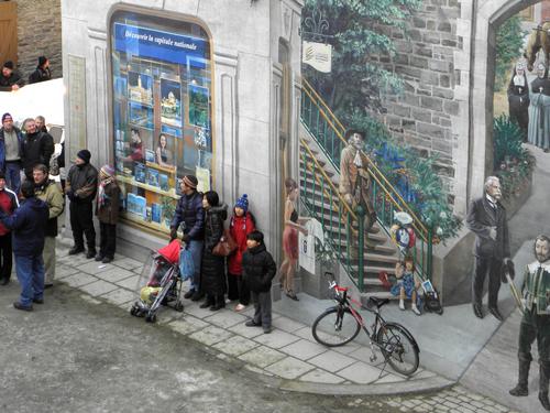 tourists watch the Ice Race before a clever 3D wall mural in Quebec City, Canada