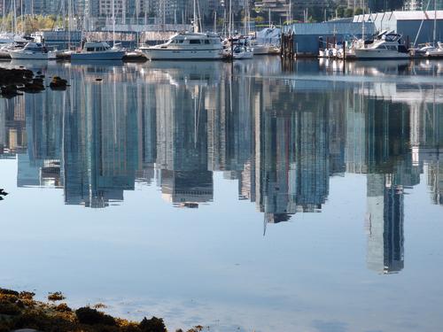yachts and reflected cityscape on Vancouver's harbor at British Columbia in Canada