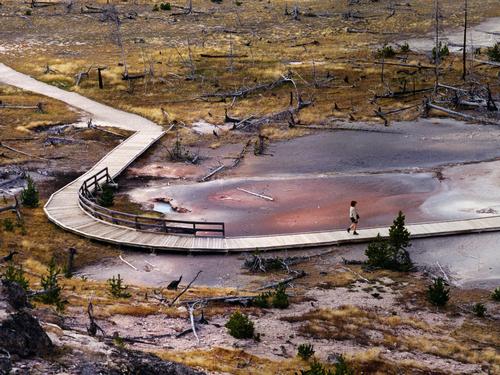 a lone tourist traverses a walkway at Yellowstone National Park, Wyoming
