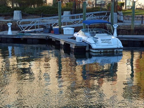 quiet boat at dock by a Boston harbor-front apartment in a re-imagined old wharf building