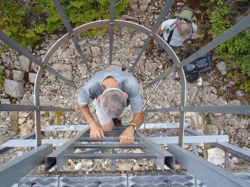 hiker descending a ladder from the summit tower on Coburn Mountain in Maine