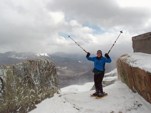 early-spring hiker frolicing on the stormy summit of Mount Garfield in New Hampshire