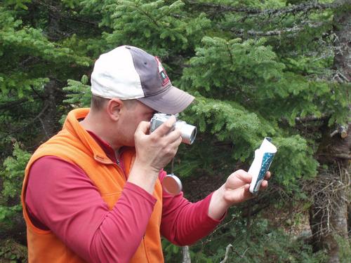 hiker photographing the summit register on Mount Kent in Maine