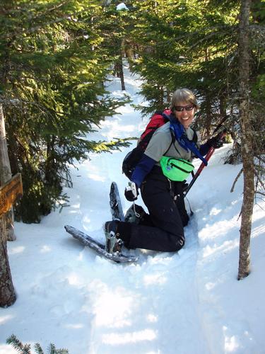 winter hiker at summit sign on Mount Passaconaway in New Hampshire