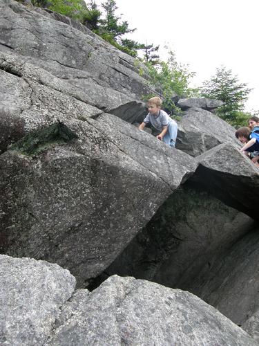 hiker ascending cliff to Mount Morgan in New Hampshire