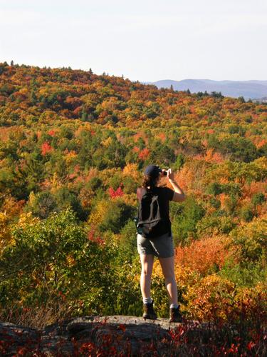 hiker and foliage view from Pinnacle Mountain in New Hampshire