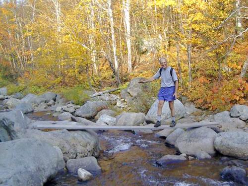 hiker crossing the South Branch of the Carrabassett River in Maine
