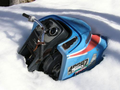 junked snowmobile in the snowy woods in New Hampshire